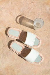 Photo of Stylish slippers and glass of water on stone floor outdoors, flat lay