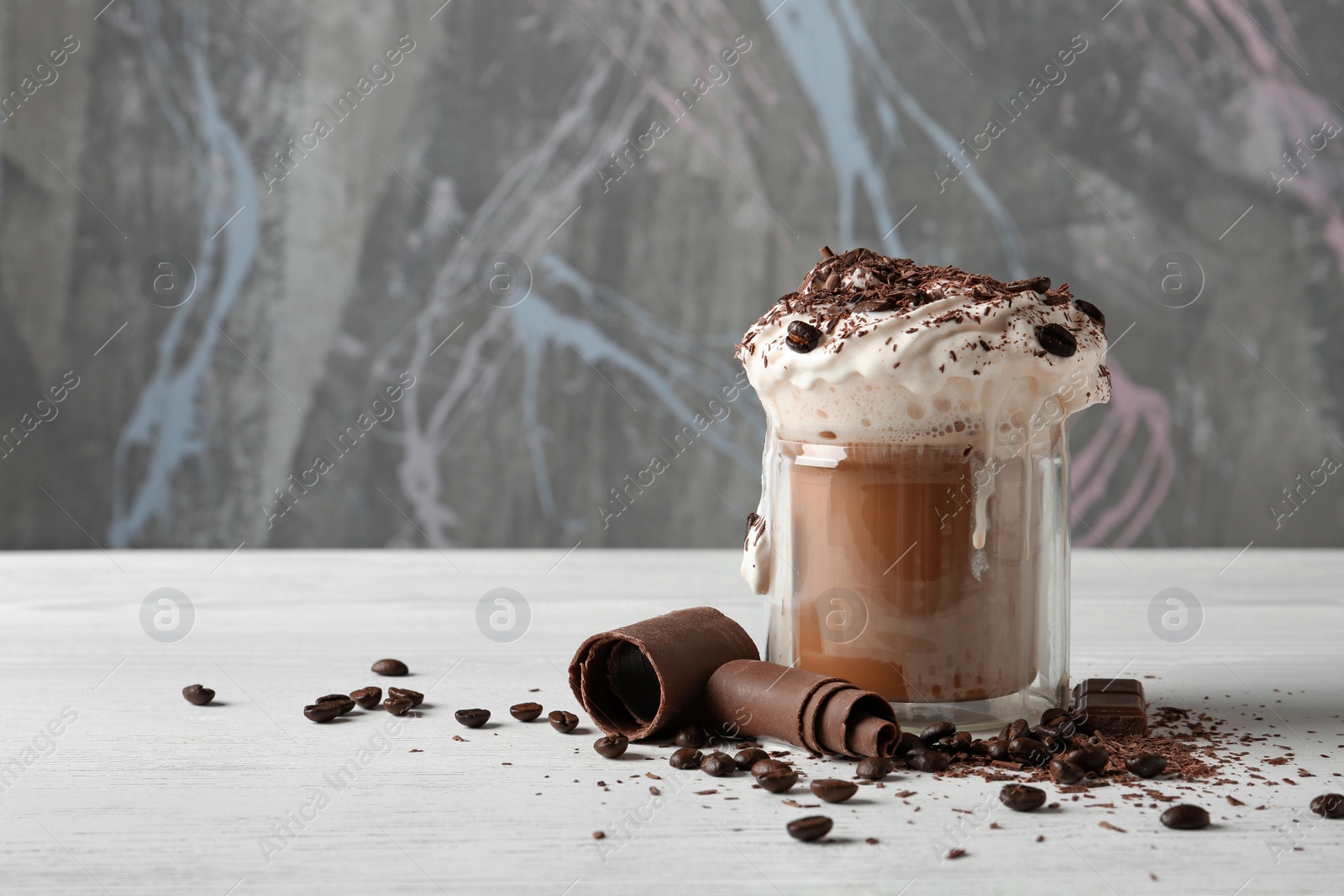 Photo of Glass cup of tasty coffee with whipped cream and chocolate on table. Space for text