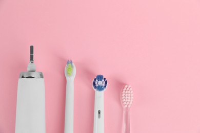 Photo of Electric toothbrush and replacement brush heads on pink background, flat lay. Space for text
