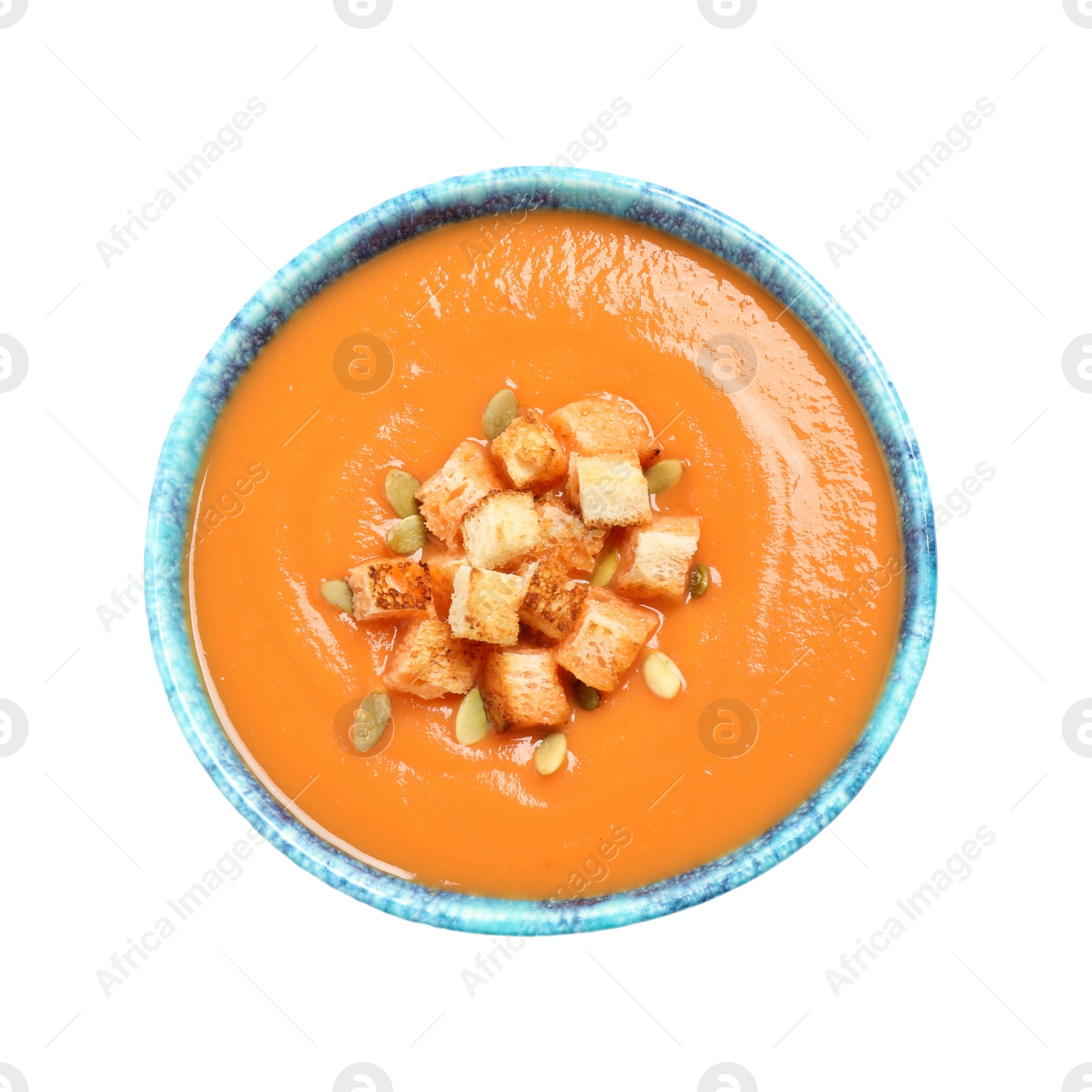 Photo of Tasty creamy pumpkin soup with croutons and seeds in bowl on white background, top view