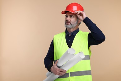 Photo of Architect in hard hat holding drafts on beige background. Space for text