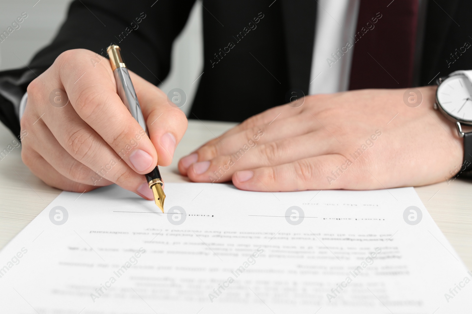 Photo of Notary signing document at wooden table, closeup