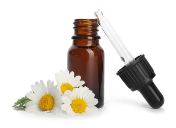 Chamomile flowers and cosmetic bottle of essential oil on white background