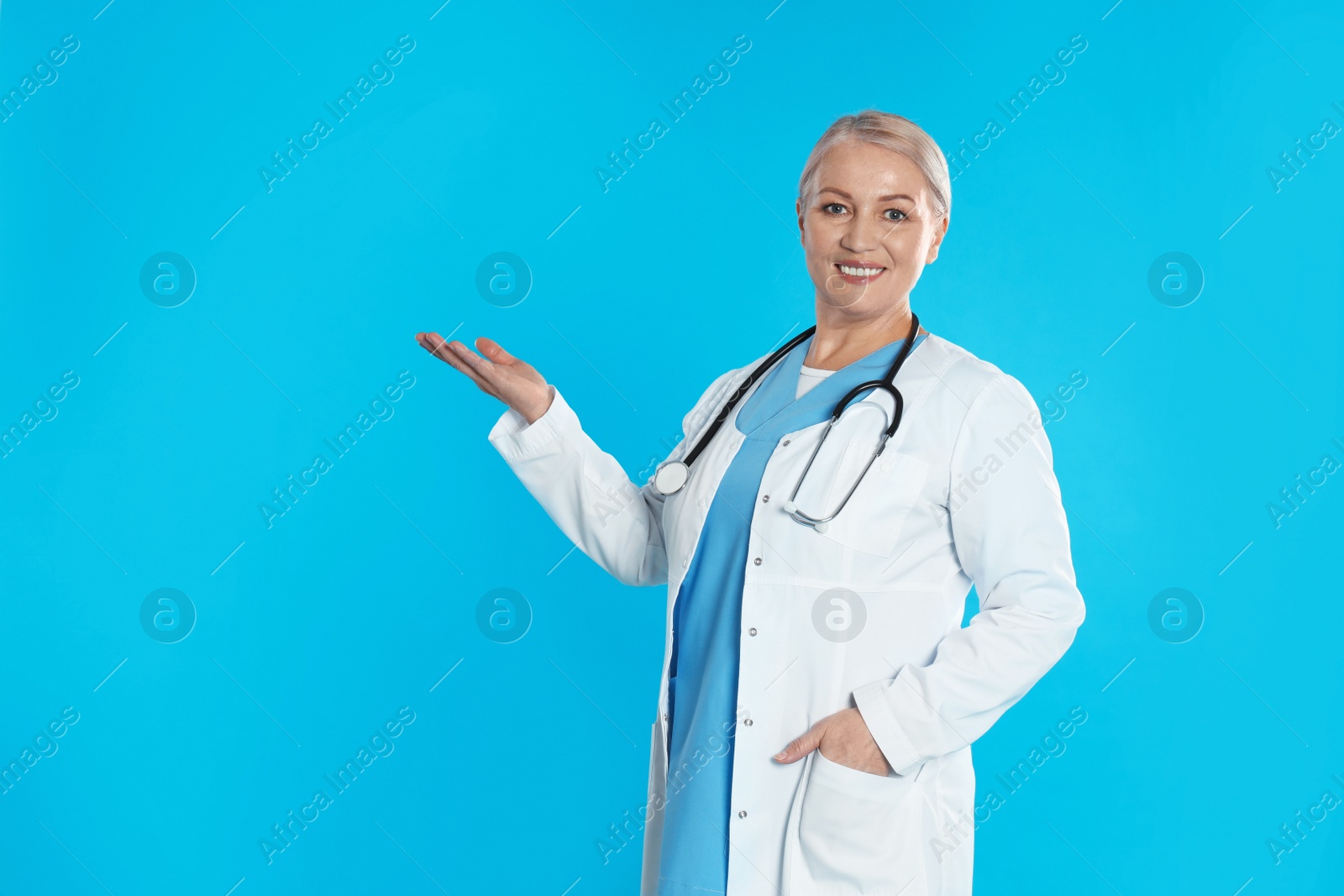 Photo of Portrait of mature doctor with stethoscope on blue background