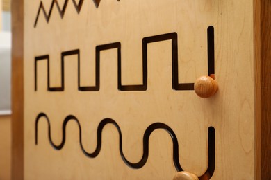 Wooden sliding maze with different lines on wall, closeup. Montessori toy