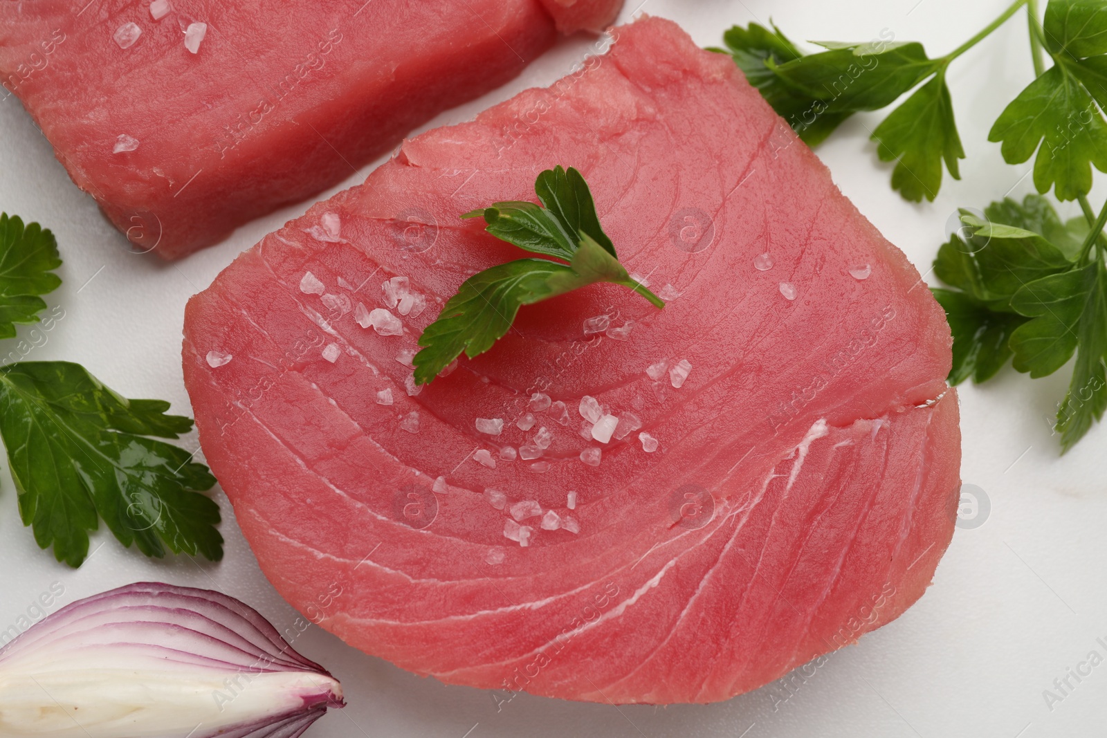 Photo of Raw tuna fillets with parsley and shallot on white table, flat lay