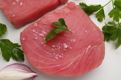 Raw tuna fillets with parsley and shallot on white table, flat lay