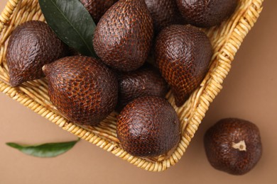 Photo of Delicious salak fruits in basket on pale brown background, top view