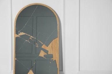 Photo of Broken mirror with many cracks near white wall. Space for text