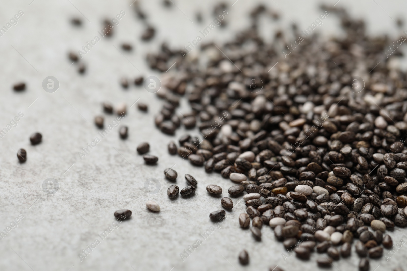 Photo of Pile of chia seeds on light grey table, closeup. Space for text