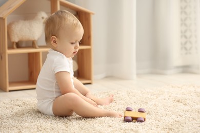 Photo of Children toys. Cute little boy with wooden car on rug at home, space for text