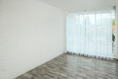 Photo of Empty room with white brick wall and large window