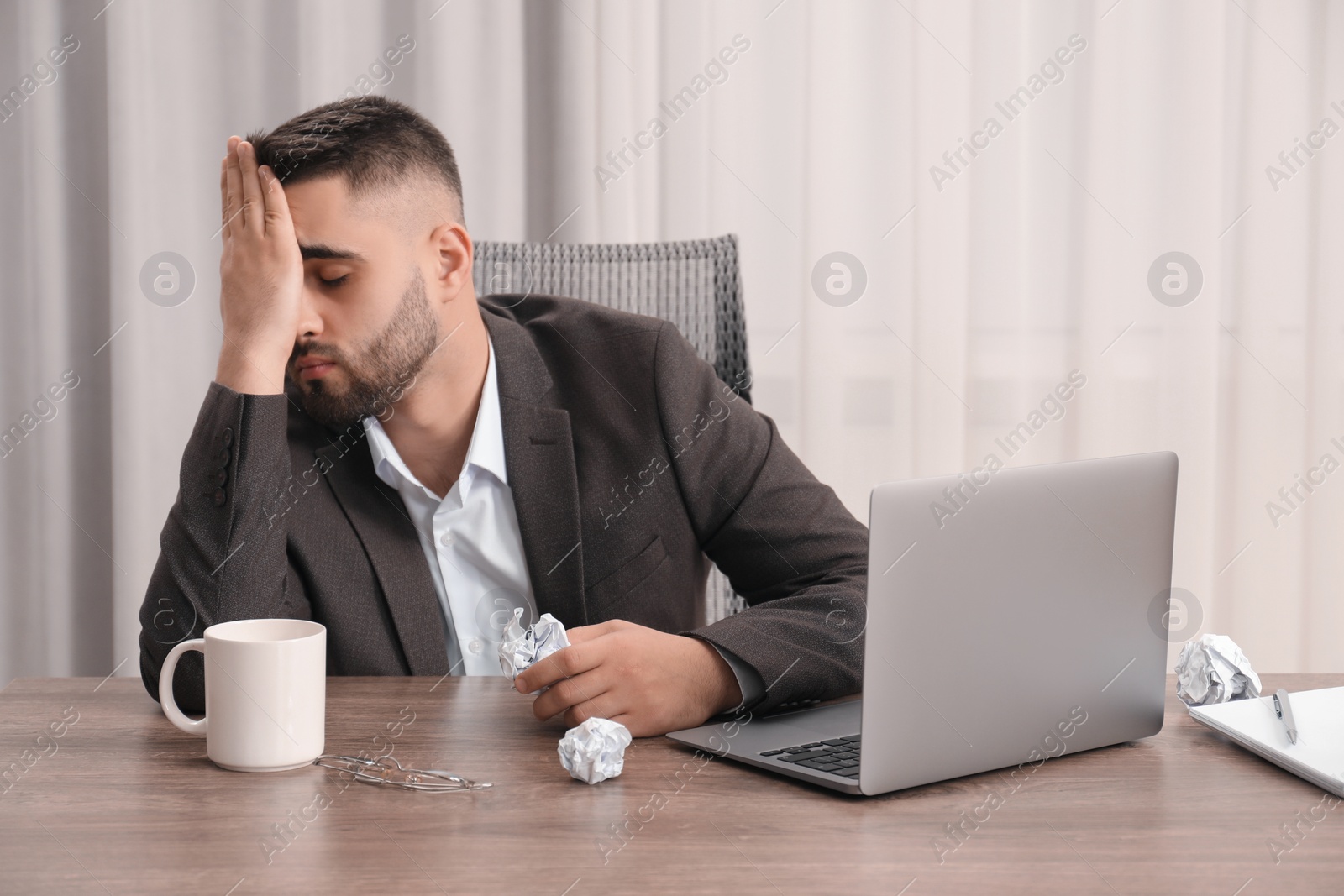 Photo of Sad businessman sitting at table in office