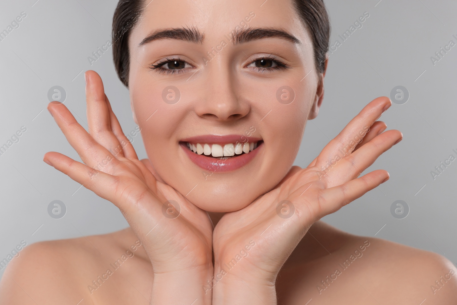 Photo of Young woman massaging her face on grey background