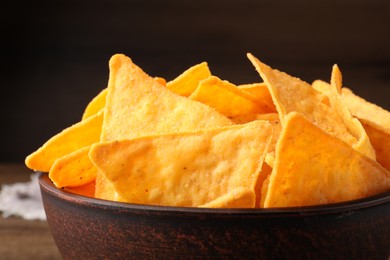 Photo of Tortilla chips (nachos) in bowl on table against dark background, closeup