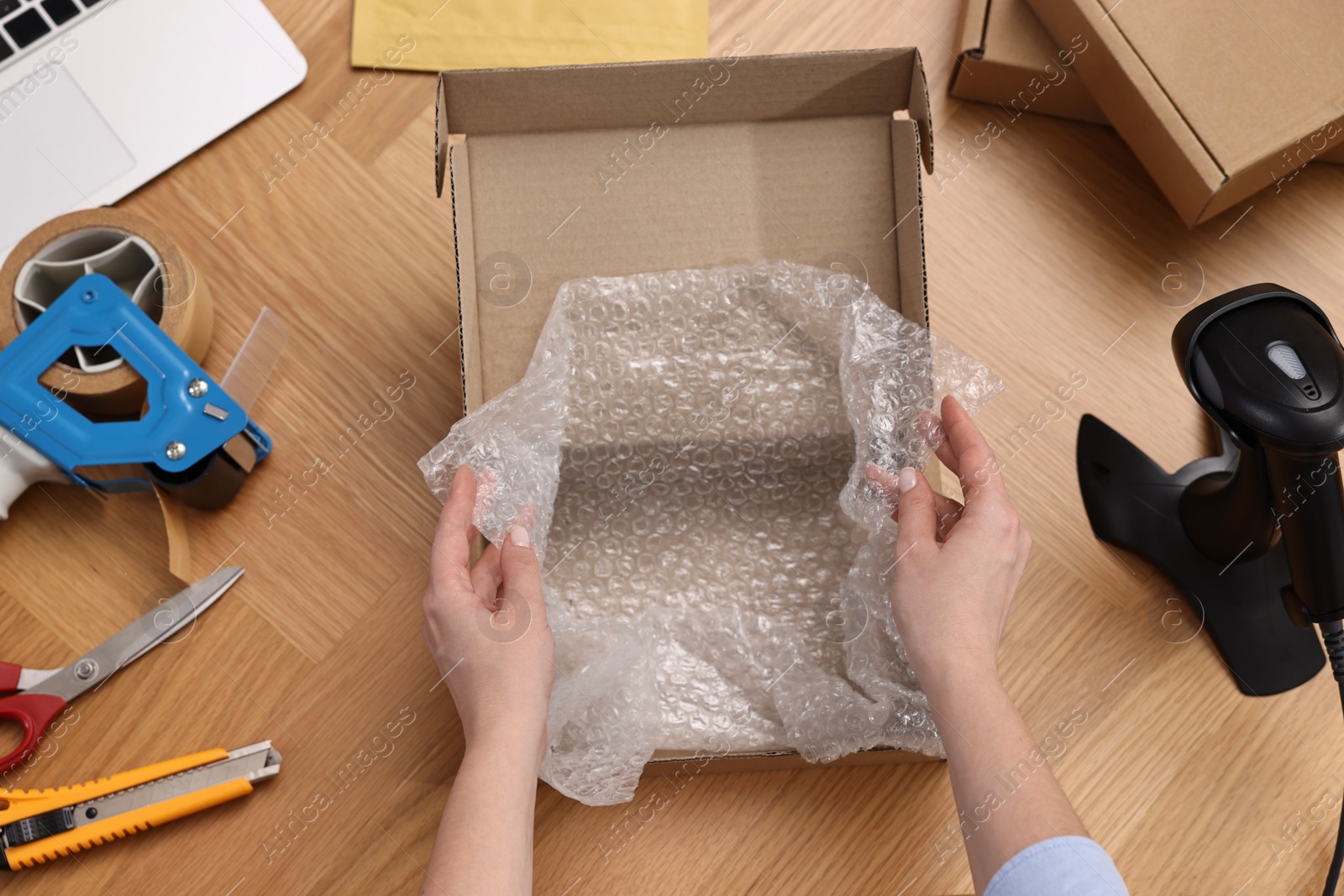 Photo of Post office worker packing parcel at wooden table, top view