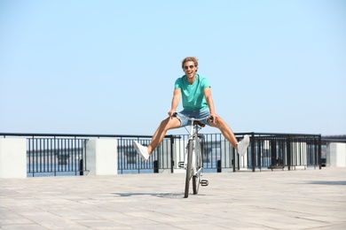 Handsome young man riding bicycle outdoors on sunny day