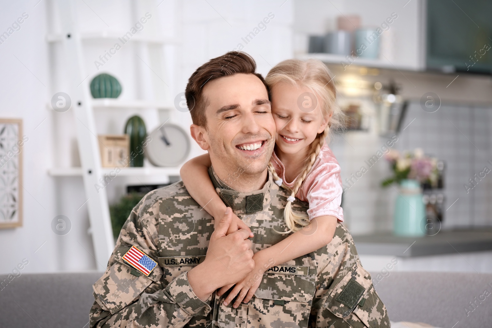 Photo of Young man in military uniform with his little daughter at home