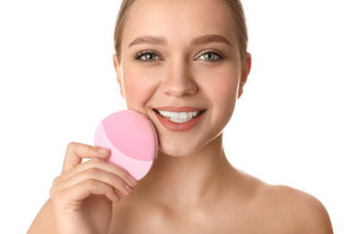 Young woman washing face with cleansing brush on white background. Cosmetic product
