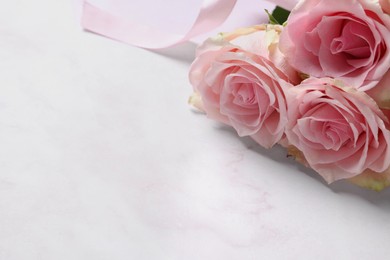 Photo of Beautiful bouquet of roses on light pink marble table, space for text. Happy birthday greetings