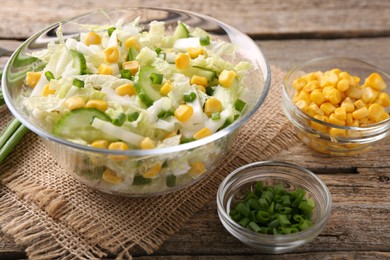 Photo of Tasty salad with Chinese cabbage, corn and green onion on wooden table, closeup