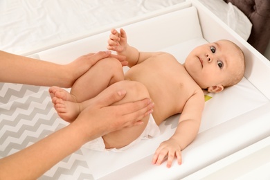 Mother and her cute child on changing table, above view. Baby massage and exercises