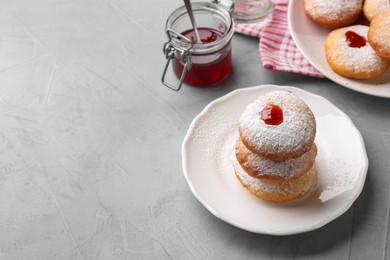 Photo of Hanukkah donuts with jelly and powdered sugar on light grey table, space for text