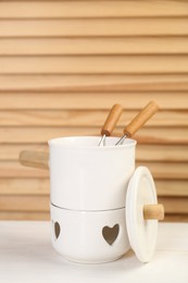 Photo of Fondue set on white wooden table, space for text