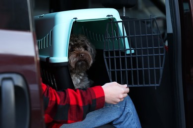 Photo of Woman with pet carrier travelling with her dog by car, closeup. Safe transportation