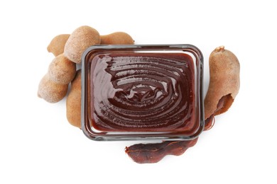 Photo of Bowl of tasty tamarind sauce and fresh pods isolated on white, top view