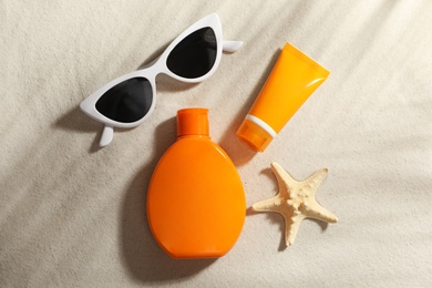 Photo of Flat lay composition with sun protection cosmetic products on sand