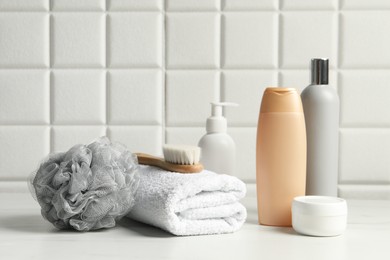 Photo of Different bath accessories and personal care products on white table near tiled wall