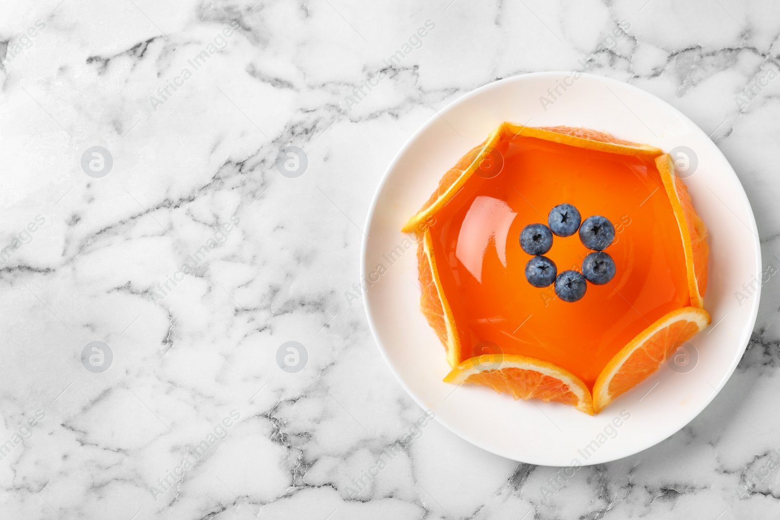 Photo of Delicious fresh jelly with orange slices and blueberries on marble table, top view. Space for text