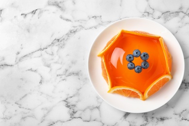 Delicious fresh jelly with orange slices and blueberries on marble table, top view. Space for text