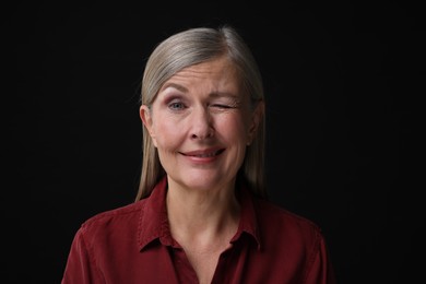 Photo of Personality concept. Portrait of woman winking on black background