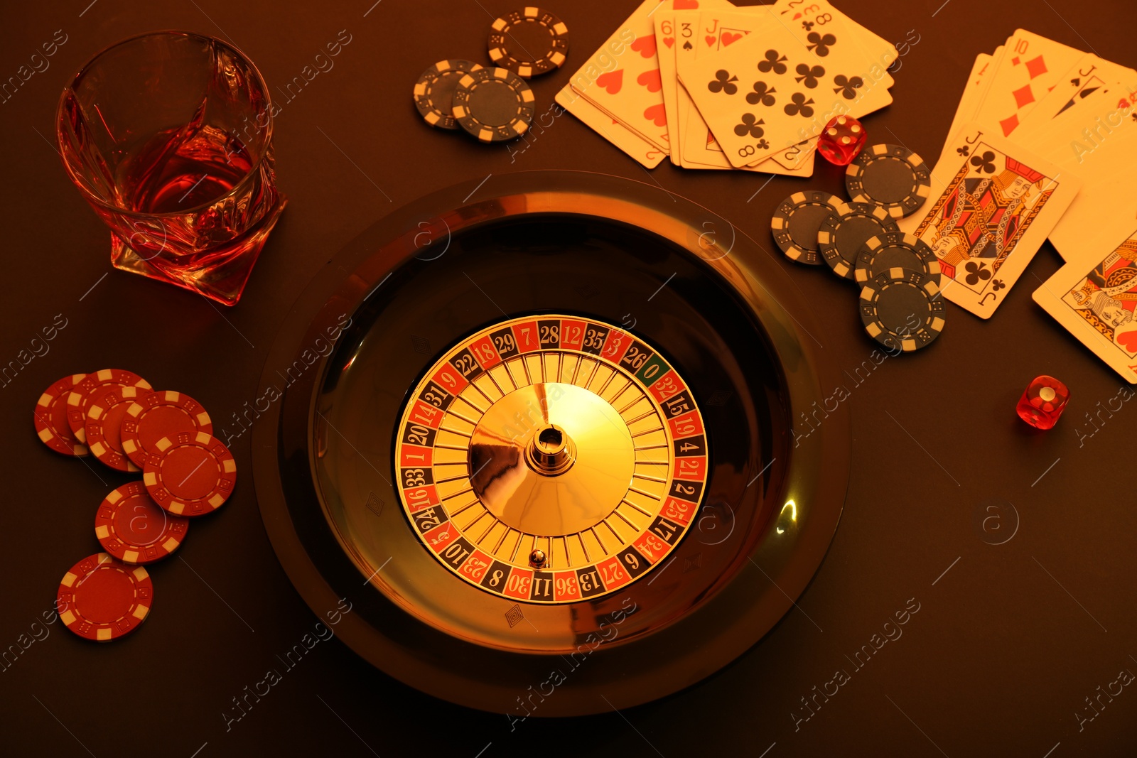 Photo of Roulette wheel, playing cards and chips on table, above view. Casino game