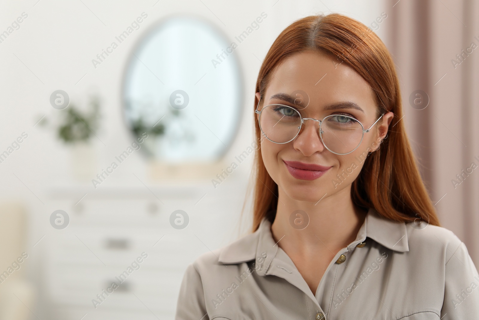 Photo of Portrait of beautiful young woman with red hair at home. Attractive happy lady looking into camera. Space for text
