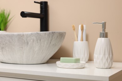 Photo of Different bath accessories and personal care products near sink on bathroom vanity