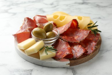 Photo of Serving board with delicious cured ham, cheese, sausage and olives on white marble table