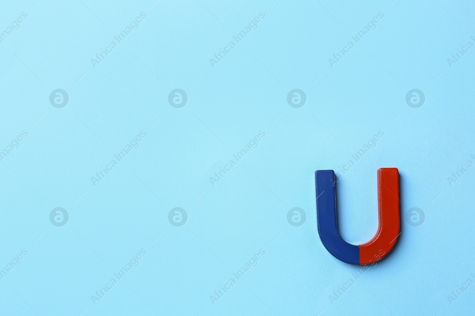 Photo of Horseshoe magnet on light blue background, top view. Space for text
