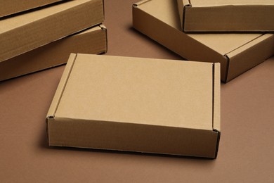Photo of Many closed cardboard boxes on brown background, closeup
