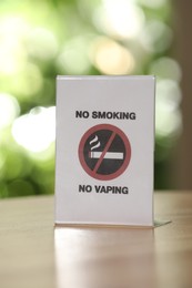 No Smoking No Vaping sign on wooden table against blurred background, closeup