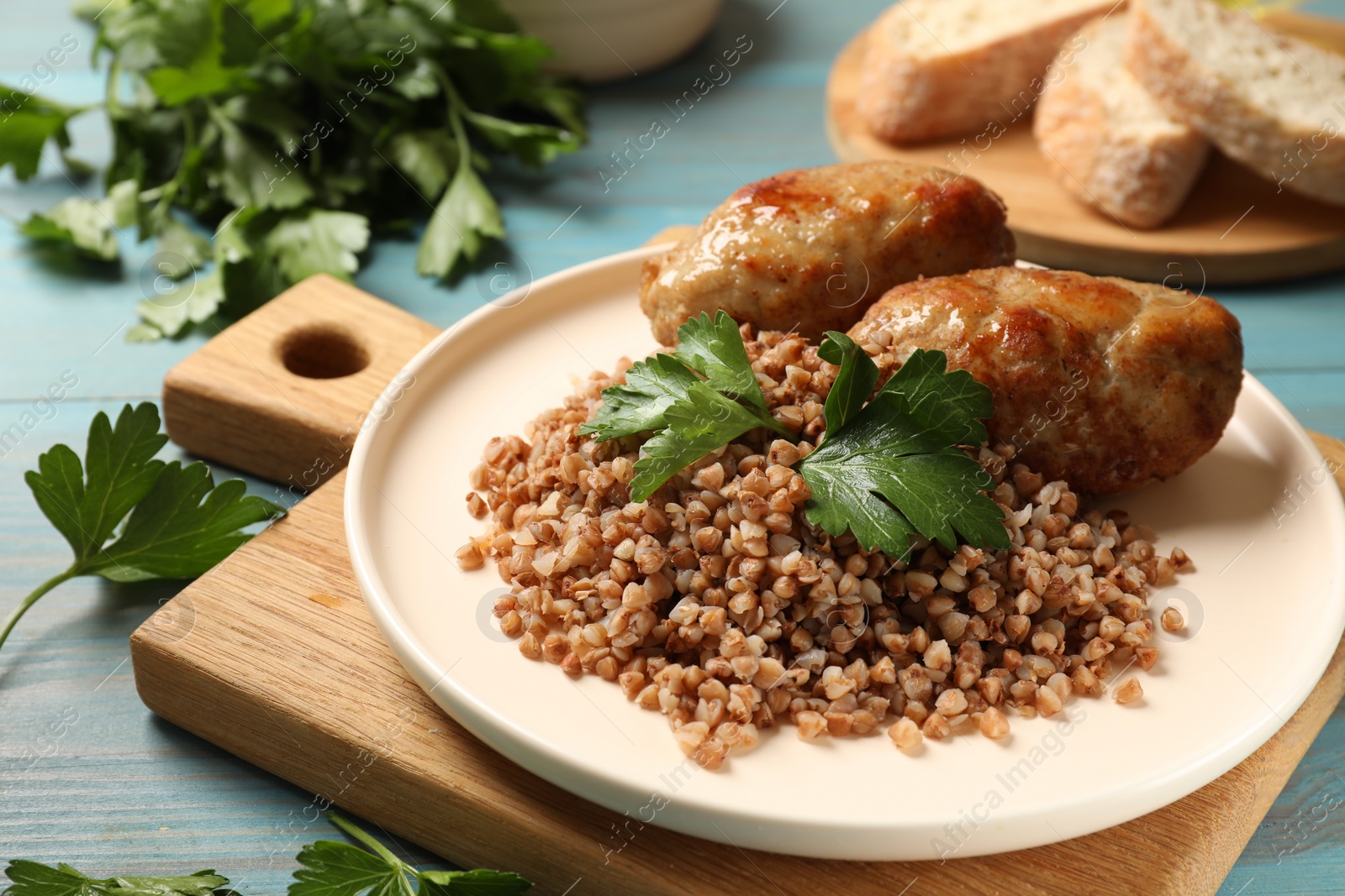 Photo of Tasty buckwheat with fresh parsley and cutlets on light blue wooden table, closeup