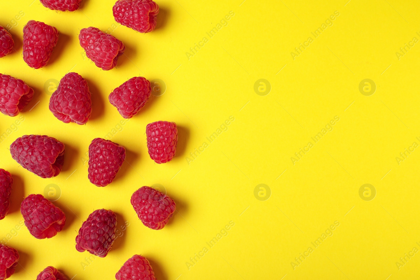 Photo of Flat lay composition with delicious ripe raspberries on yellow background. Space for text