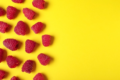 Flat lay composition with delicious ripe raspberries on yellow background. Space for text