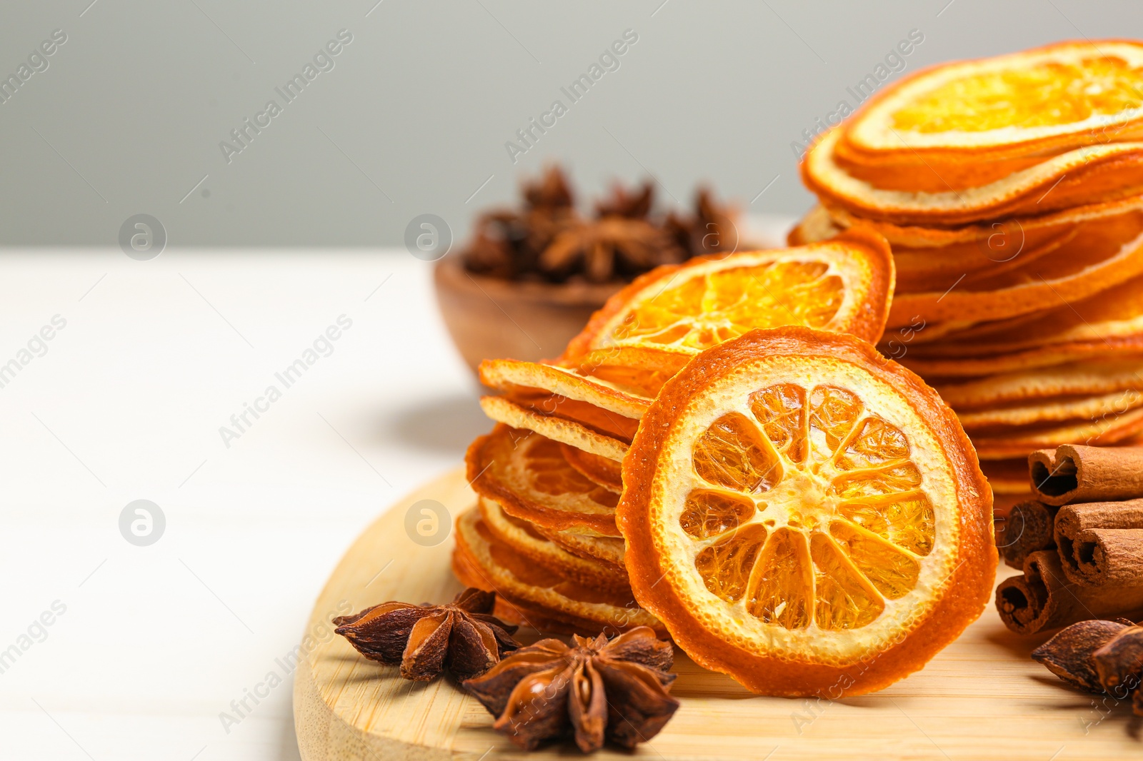 Photo of Dry orange slices, anise stars and cinnamon sticks on white table, closeup. Space for text