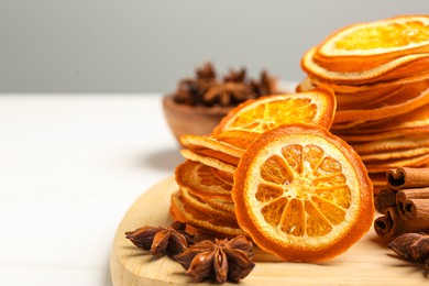 Dry orange slices, anise stars and cinnamon sticks on white table, closeup. Space for text