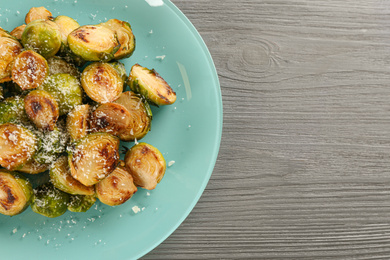 Photo of Delicious roasted brussels sprouts with grated cheese on grey wooden table, top view. Space for text