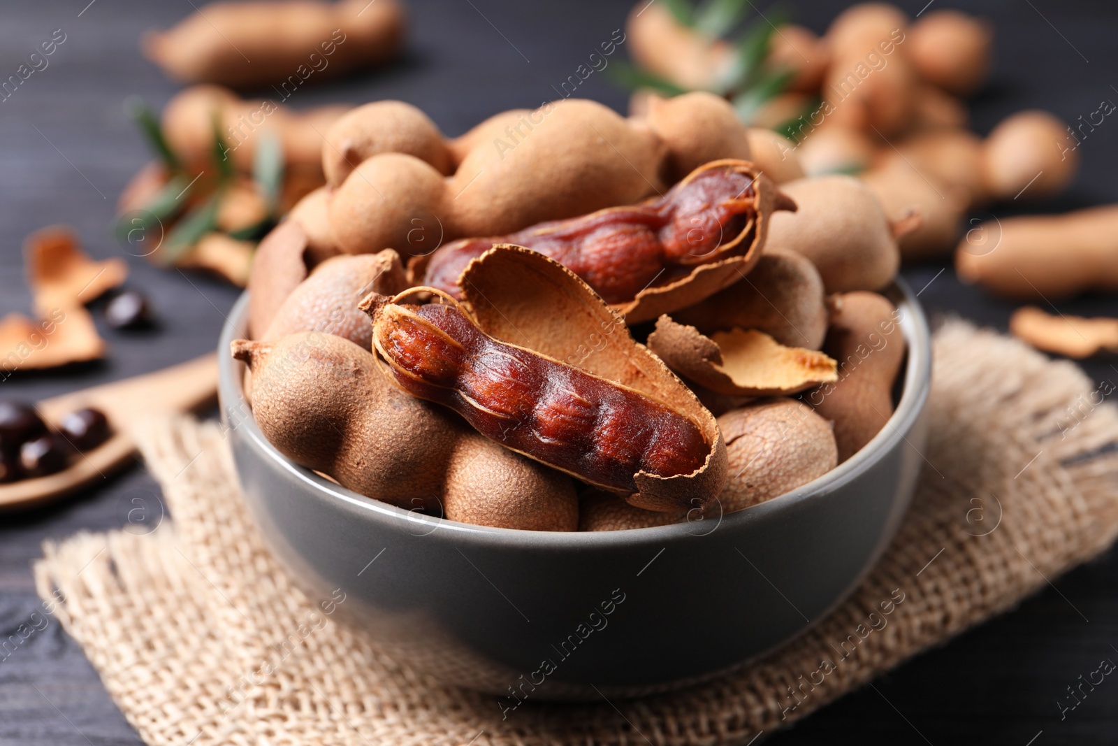 Photo of Delicious ripe tamarinds in ceramic bowl on table, closeup