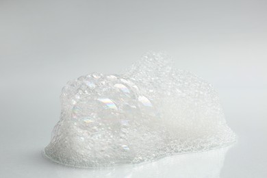 Drop of fluffy bath foam on light background